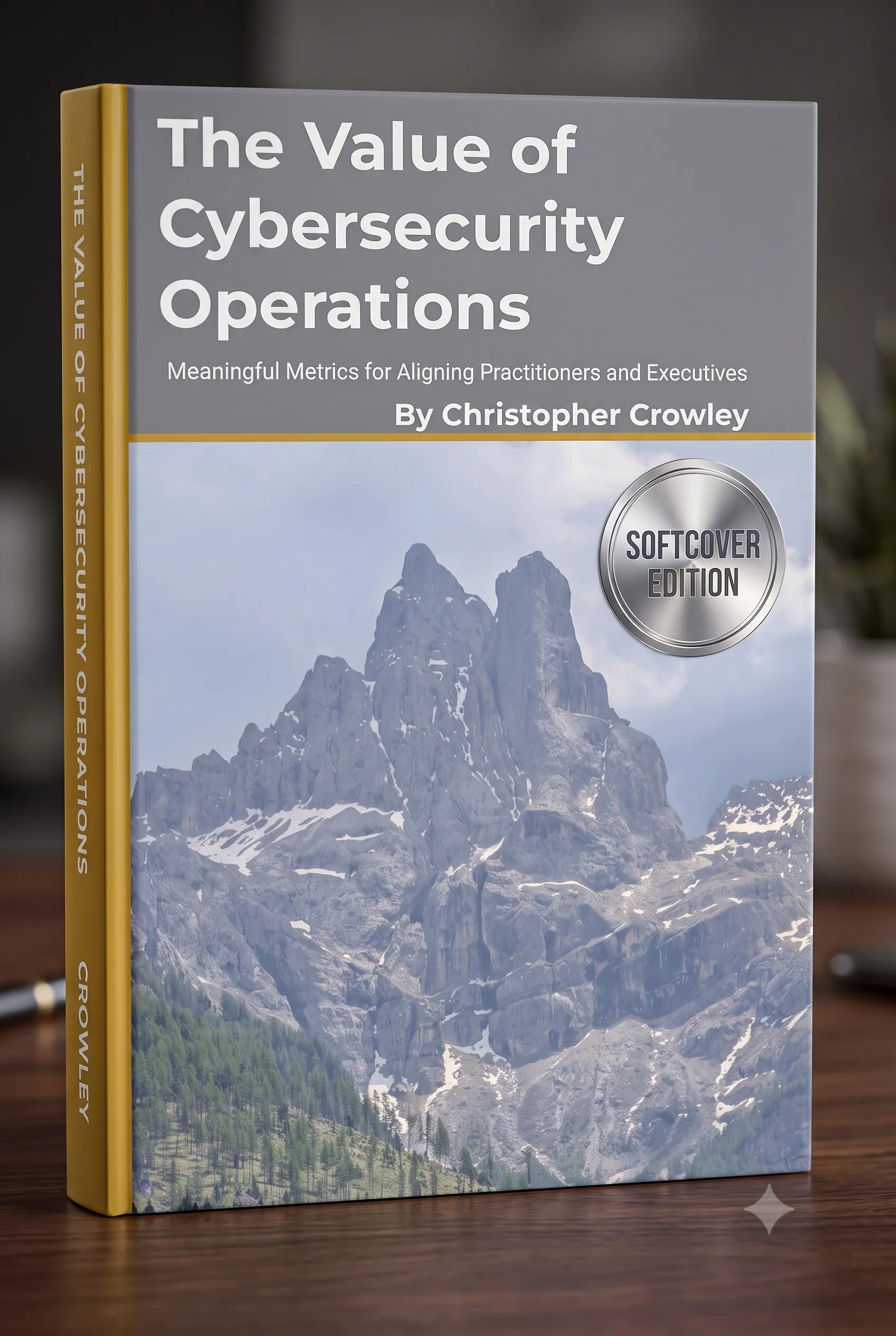 A book titled "The Value of Cybersecurity Operations" by Christopher Crowley, shown standing upright on a wooden surface with a blurred indoor background. The cover features a mountain landscape photo, a gray title band, and a gold spine.